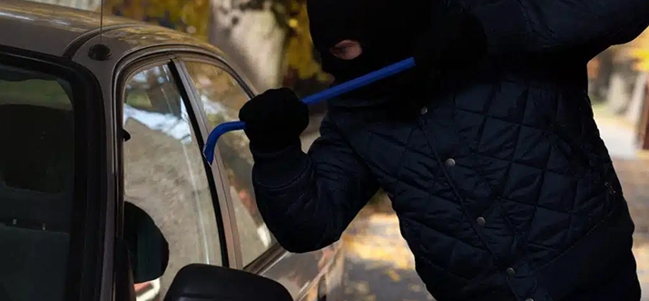 Ladrão com martelo em suas mãos quebrando janela