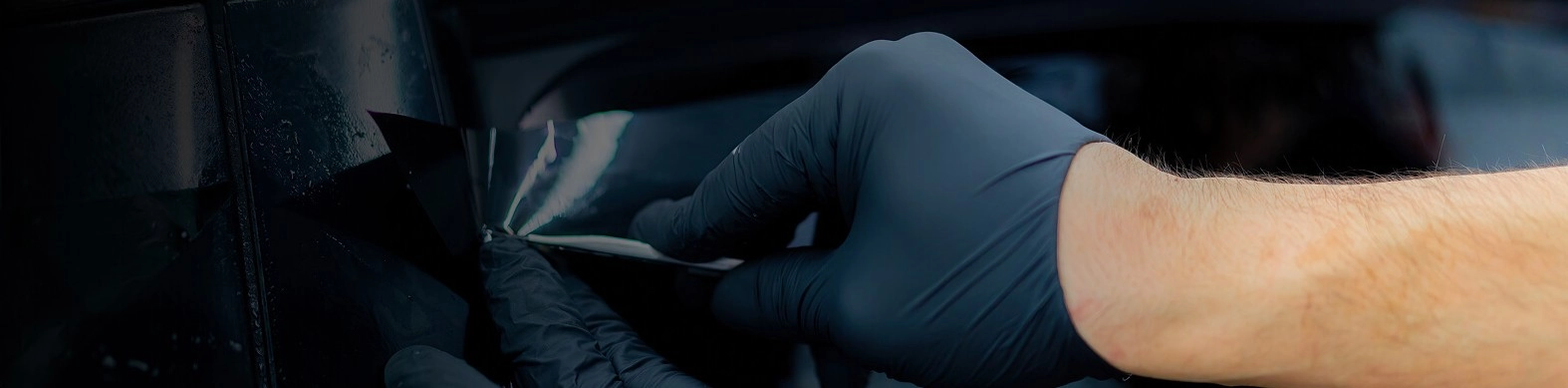 Homem com luvas em suas mãos fazendo aplicagem da película