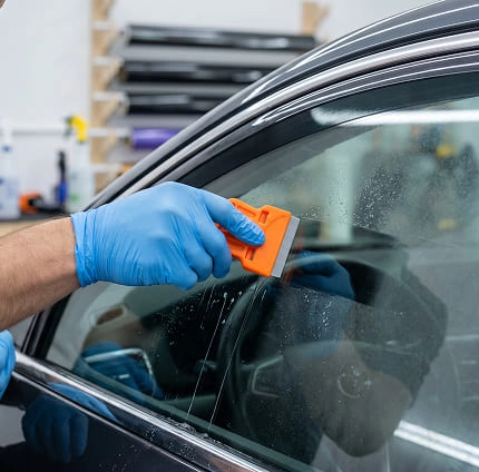 IMAGEM ILUSTRATIVA - HOMEM PASSANDO RASPADOR EM VIDRO DE CARRO