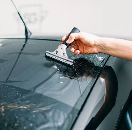 IMAGEM ILUSTRATIVA - HOMEM APLICANDO PELÍCULA EM TETO DE CARRO COM ESPÁTULA