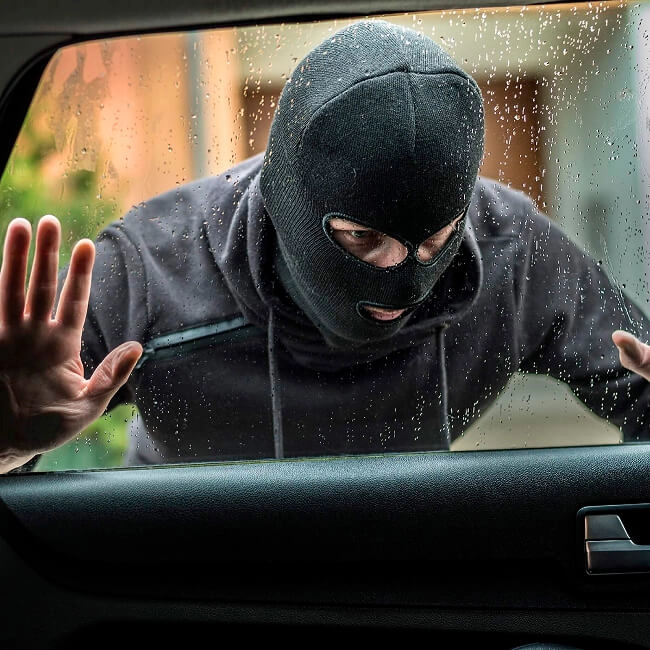 Imagem ilustrativa de um bandido olhando dentro de um carro